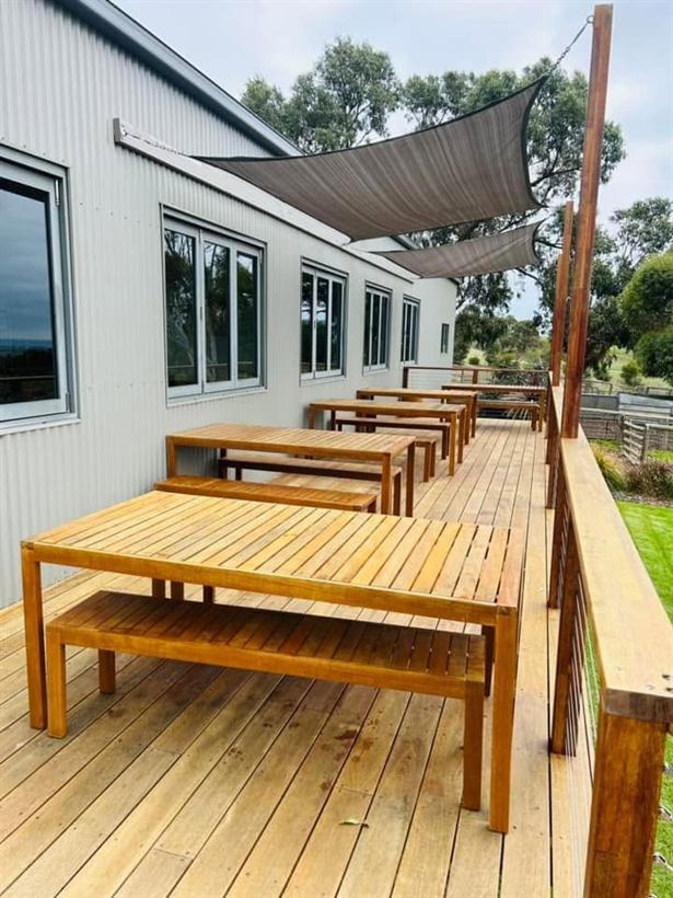 Timber tables under a shade sail on the deck