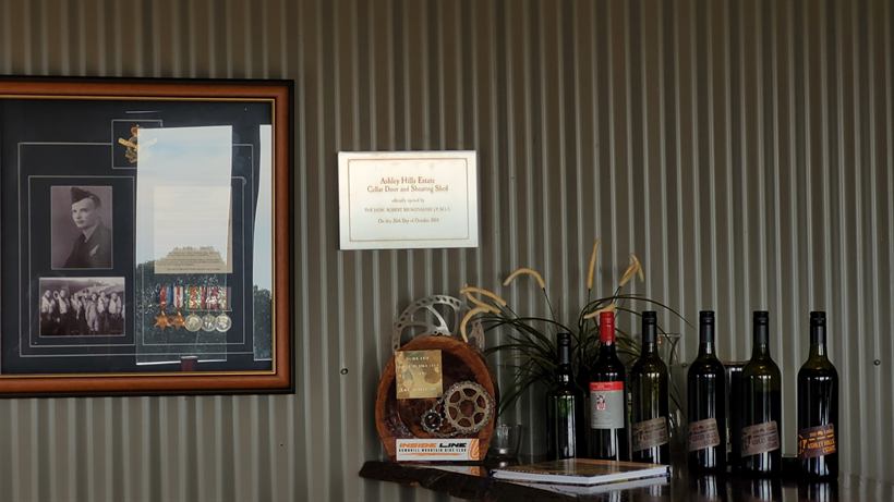 Framed Giles family photographs above a shelf of estate wines